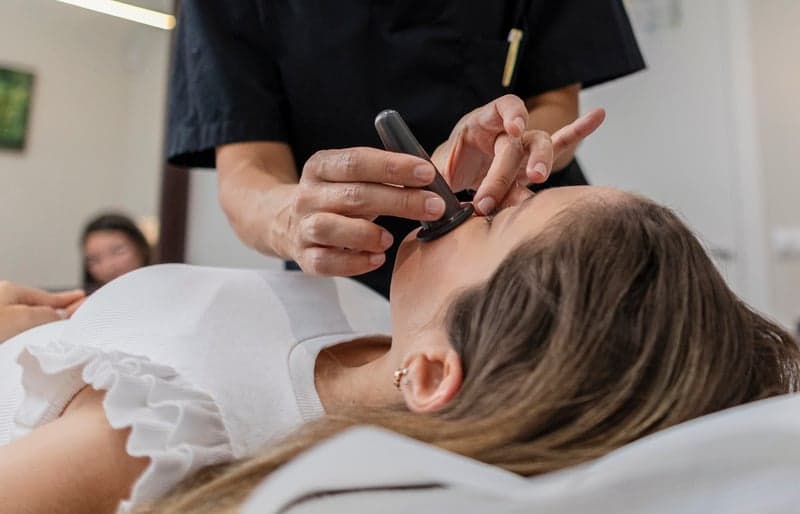 Esthetician performing a facial cupping treatment on a client.